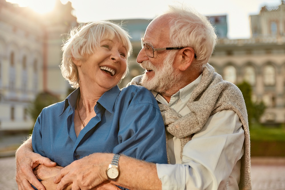 Feeling happy with you. Cheerful senior couple in casual clothing embracing each other and laughing while standing together outdoors